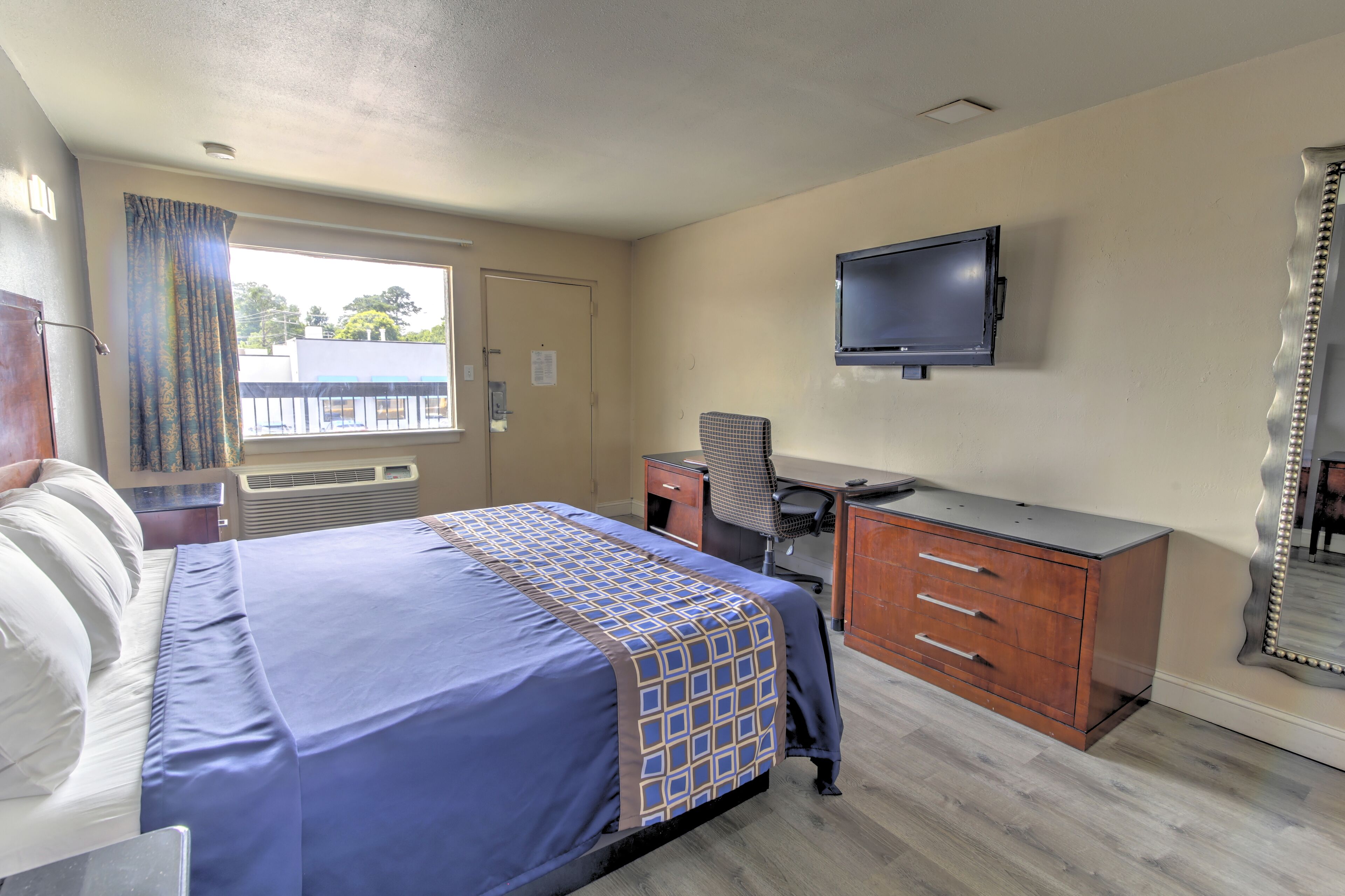 Una habitación de hotel con cama, escritorio, televisor y cómoda.