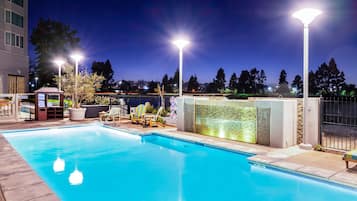 Una piscina al aire libre, sillones reclinables de piscina