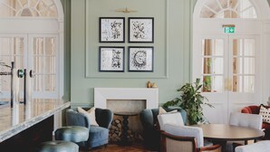 A dining area with a wooden herringbone floor, a round table, and blue upholstered chairs. - The Queens Hotel (Portsmouth)