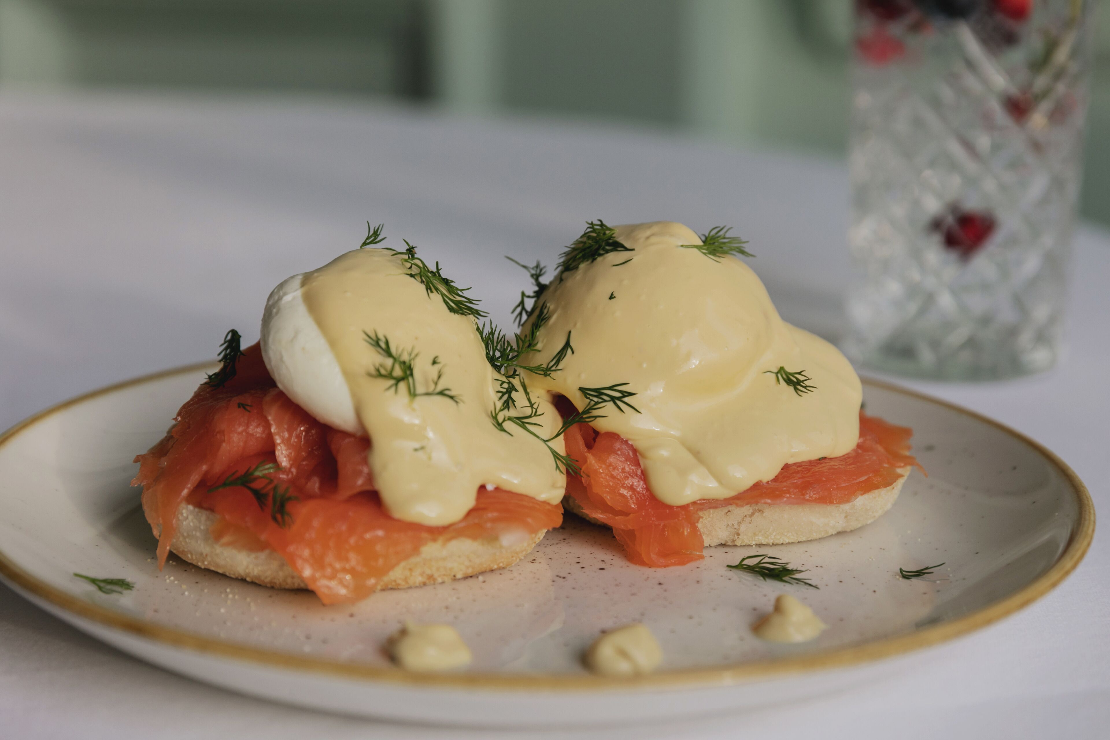 A plate with two open-faced sandwiches topped with smoked salmon and hollandaise sauce, garnished with dill.