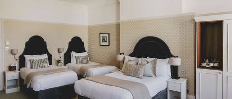 A hotel room with three beds, a wardrobe, and a chandelier.