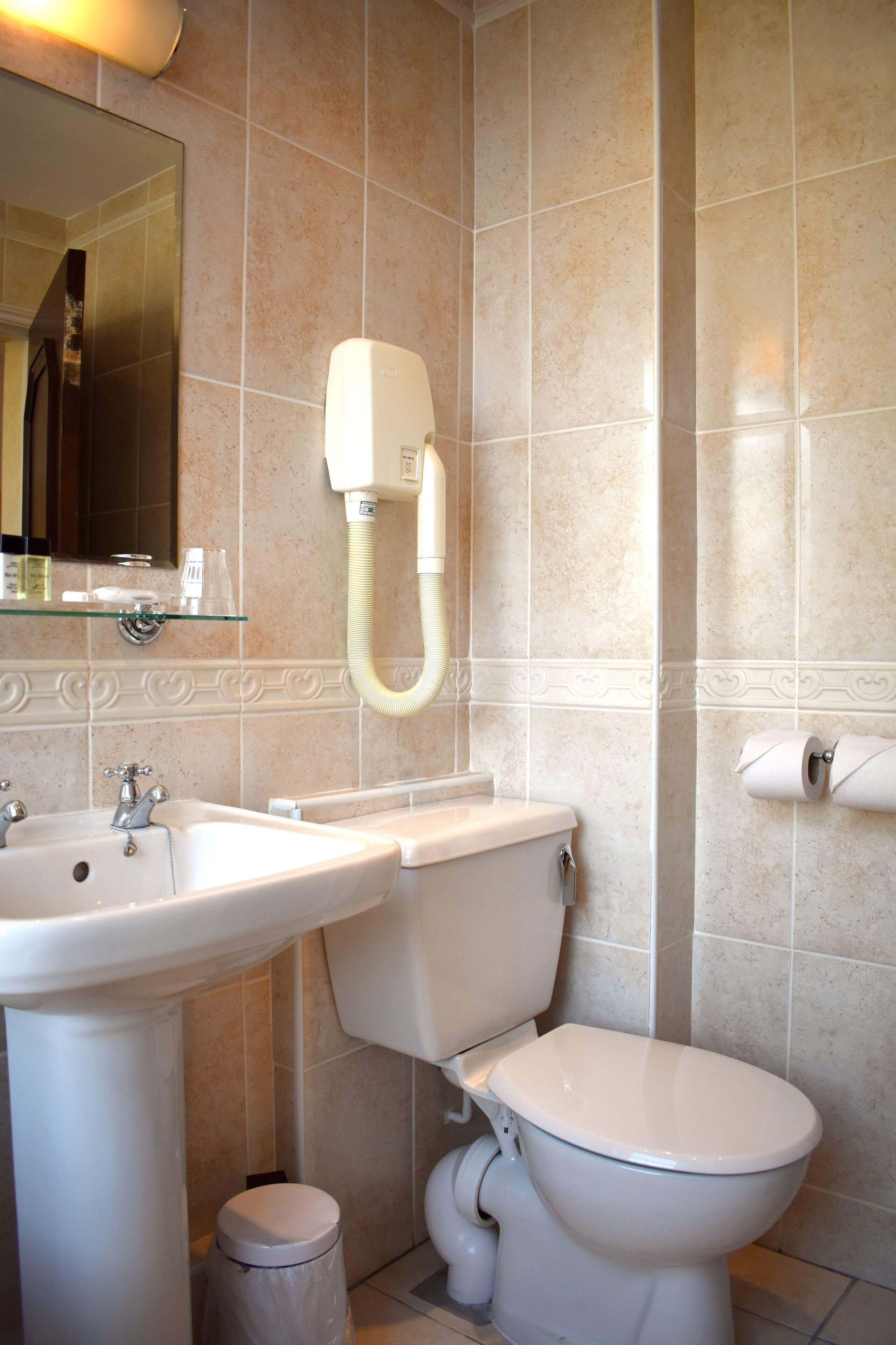 A bathroom with a sink, toilet, and a hand dryer.
