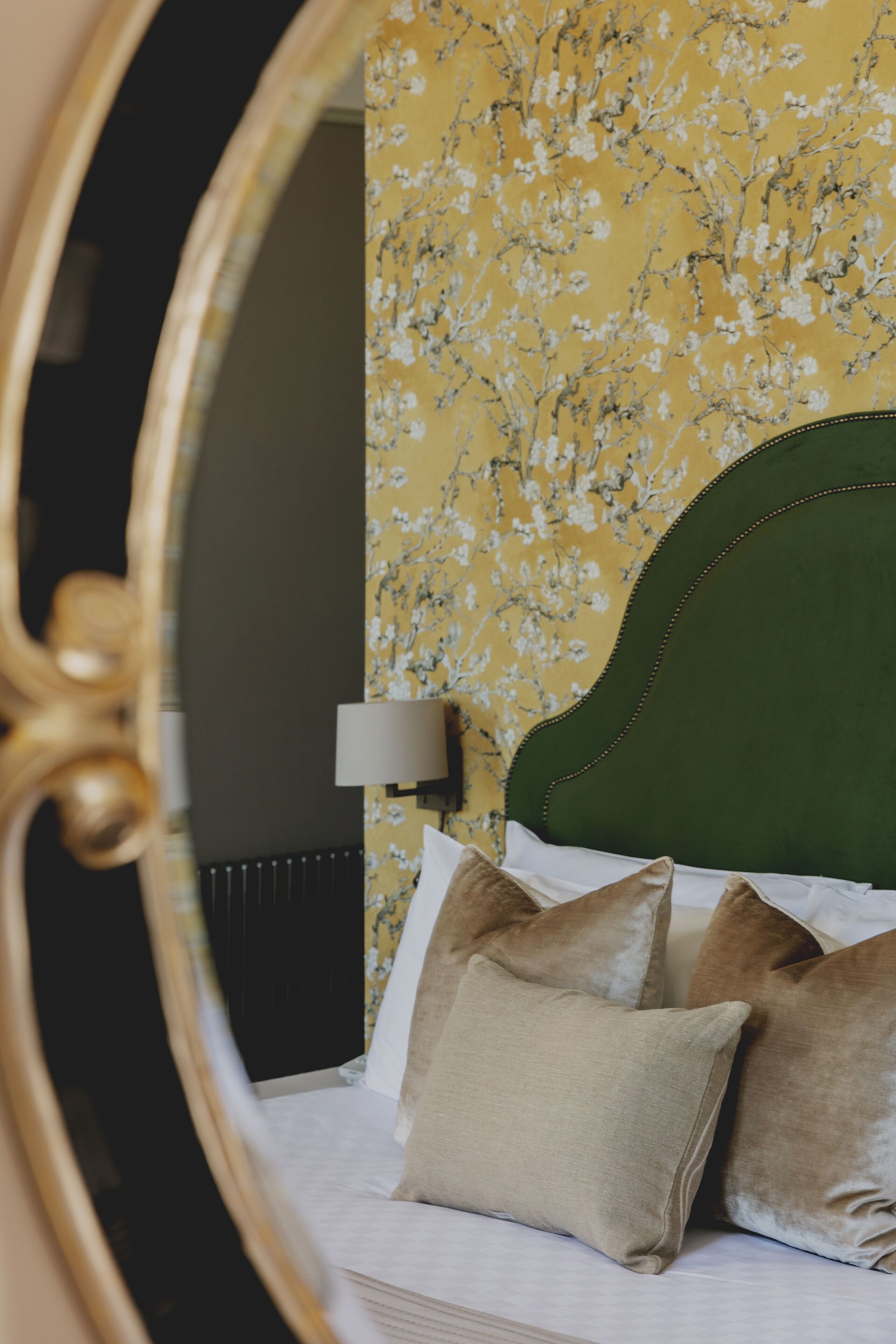 Een bed met een groen hoofdeinde, witte beddengoed en twee kussens.