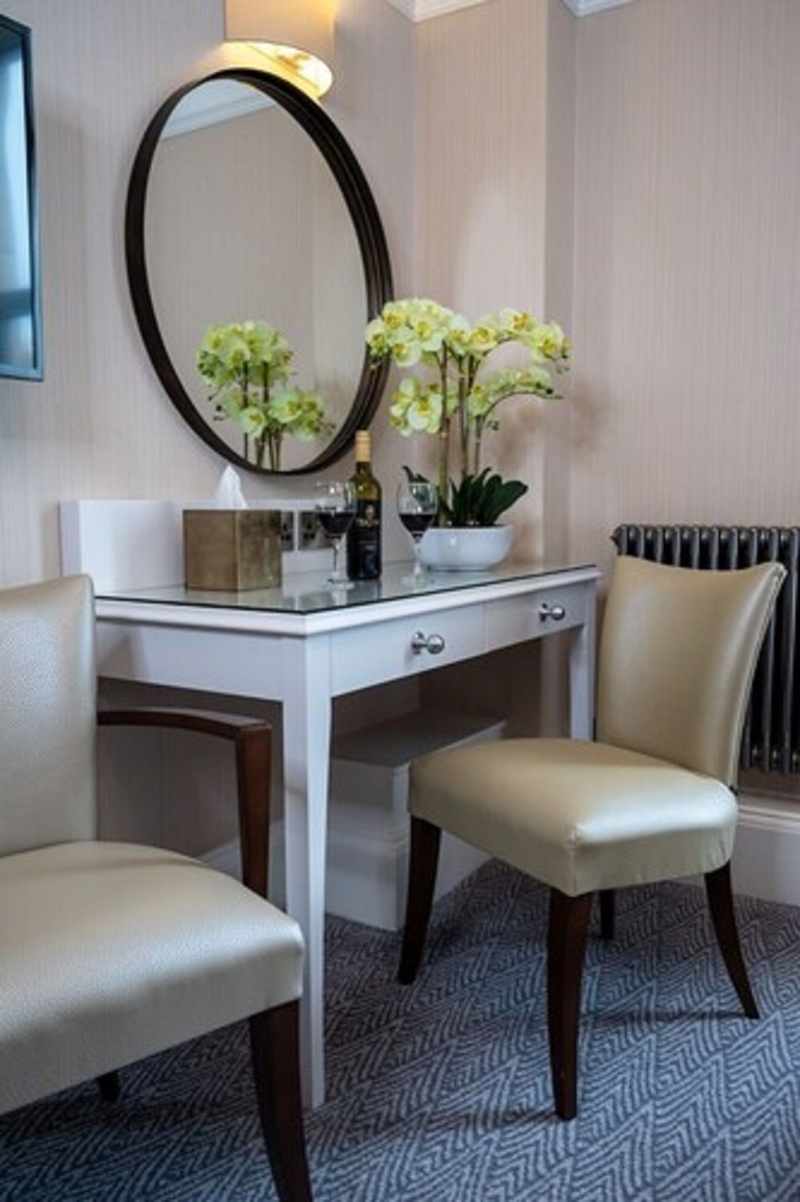 A room with a white vanity, a mirror, a chair, and a radiator.