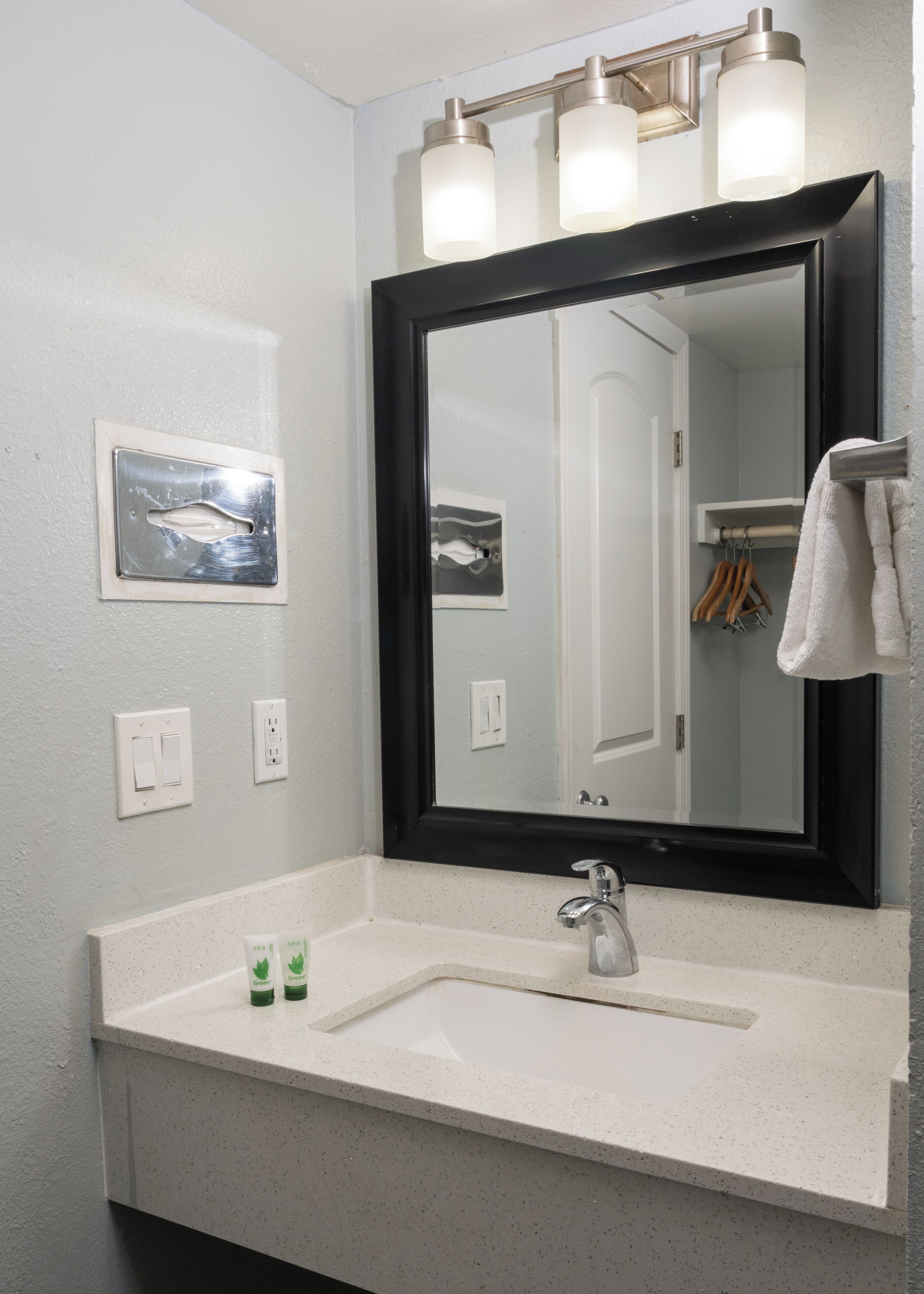 A bathroom with a large mirror, a sink, and two wall-mounted lights.