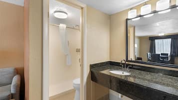 Une salle de bain avec un lavabo, un miroir et des toilettes.