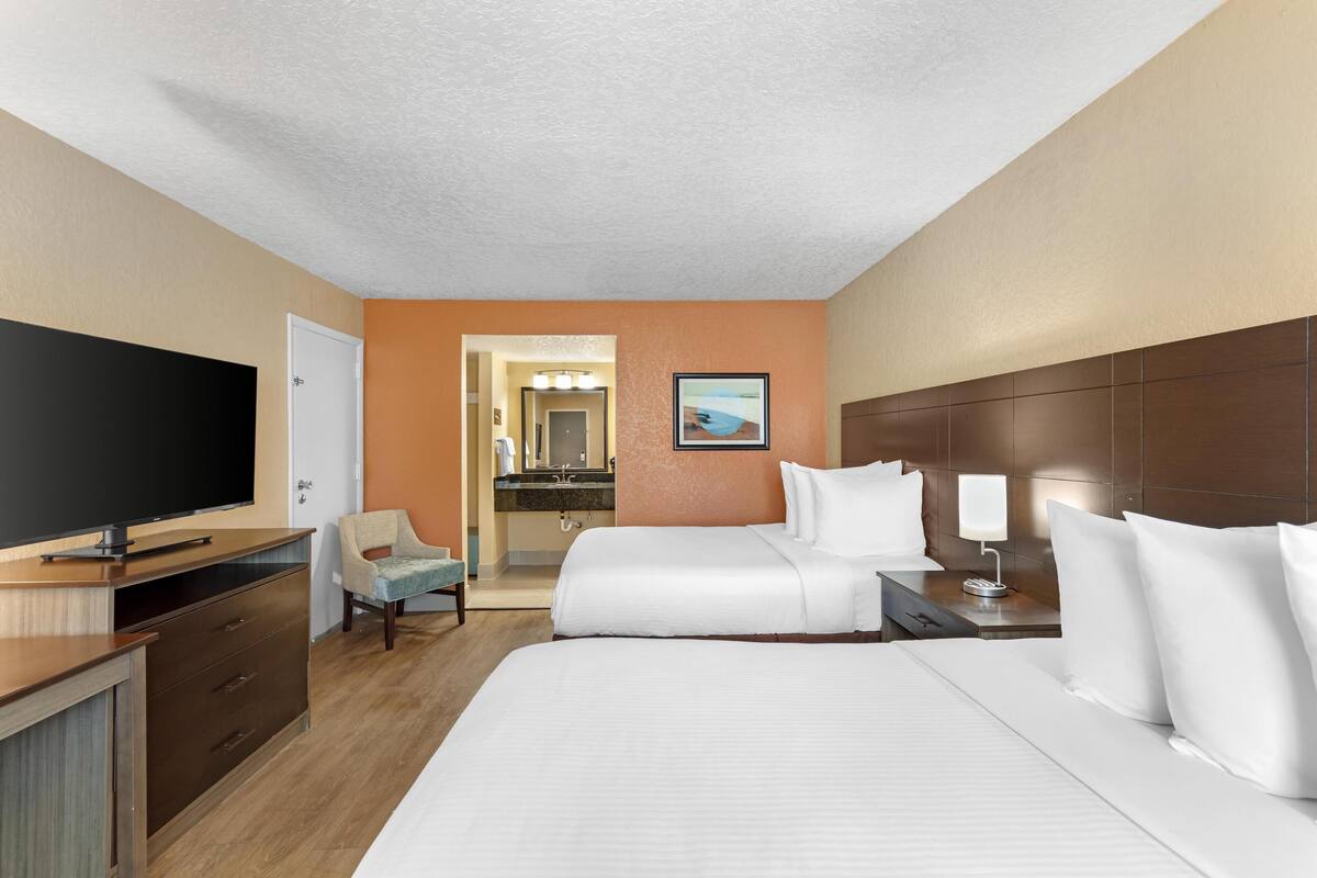 A hotel room with a large bed, a TV, a desk, and a chair.
