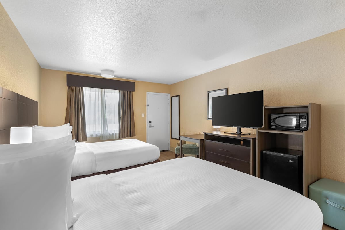 A hotel room with two beds, a television, a microwave, and a refrigerator.