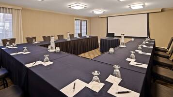 A conference room with a long table, chairs, name cards, and a projector screen.