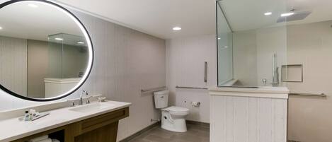 Une salle de bain moderne avec un grand miroir, deux lavabos, des toilettes et un espace douche.