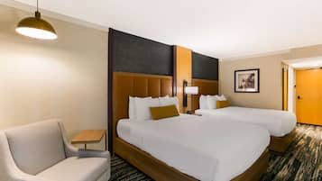 A hotel room with two beds, a sofa, a small table, and a lamp.