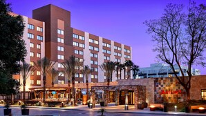 Un hôtel Marriott doté d’une piscine, de palmiers et d’une entrée bien éclairée.