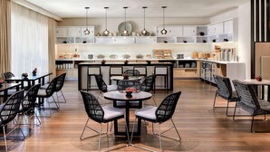 Une cuisine moderne dotée d’un îlot central, de meubles encastrés et de luminaires suspendus.