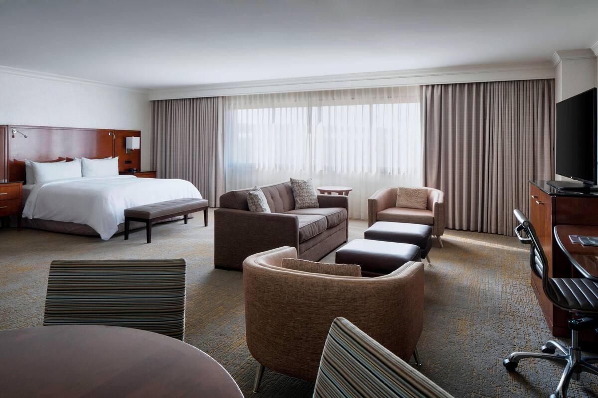 Una habitación de hotel con cama, sofá, escritorio y televisión.