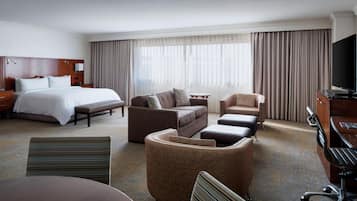 Una habitación de hotel con cama, sofá, escritorio y televisión.