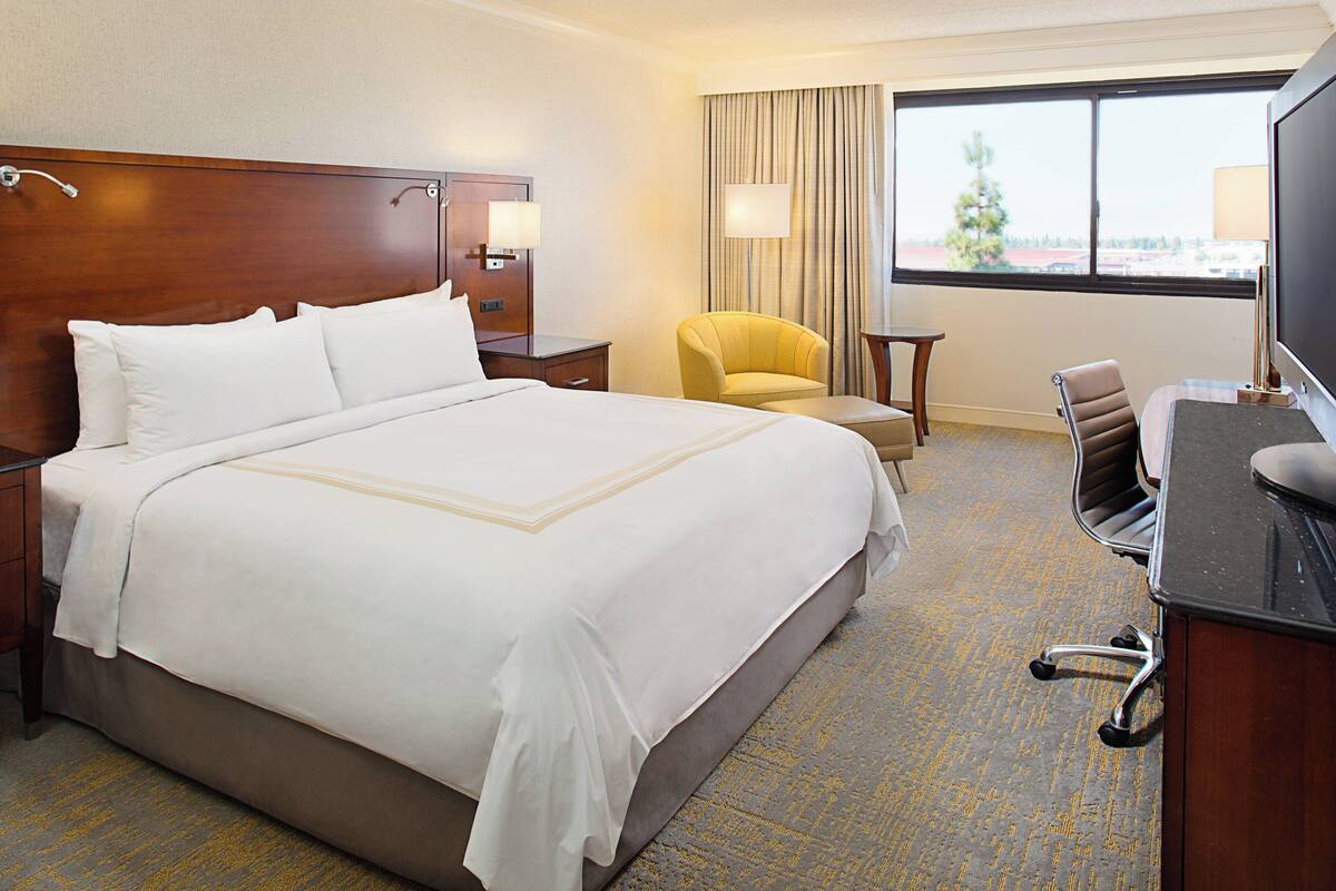Habitación de hotel con una cama grande, un escritorio, una silla y un televisor.