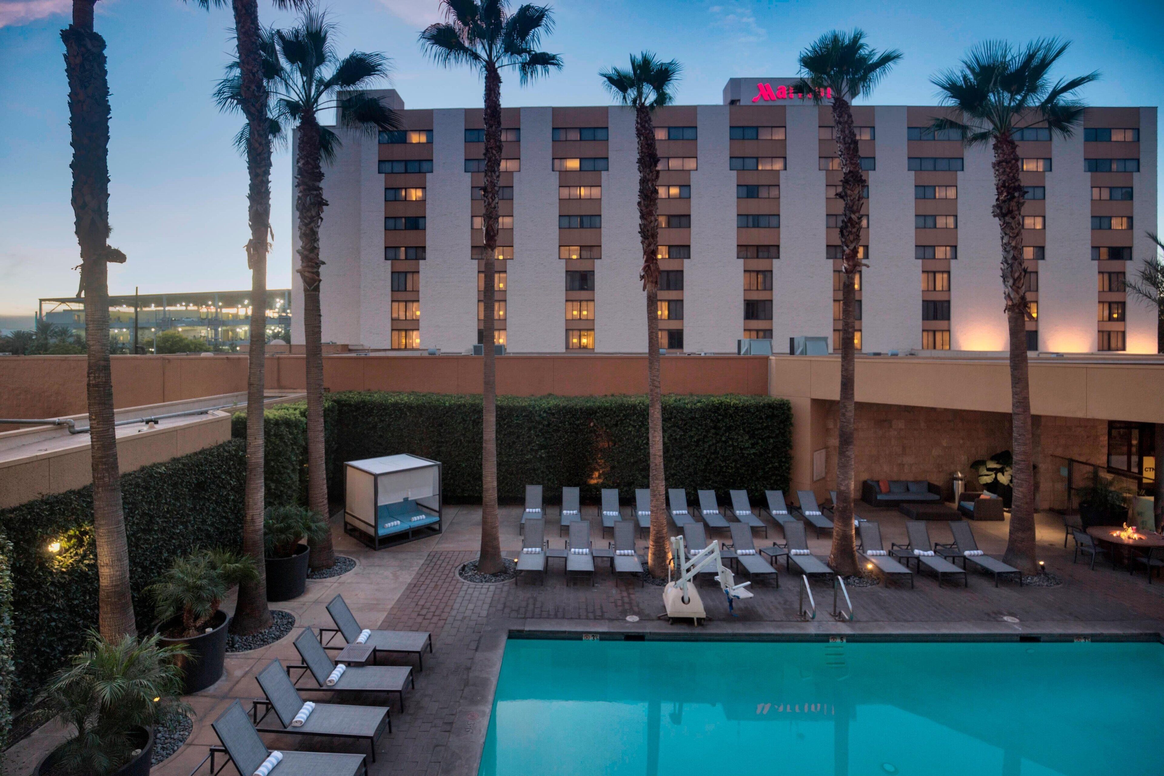 Un hôtel doté d’une piscine, de chaises longues et de palmiers.