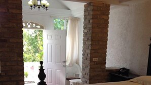 Un dormitorio con una cama grande, un candelabro, una pared de ladrillo y una puerta que da a un balcón.