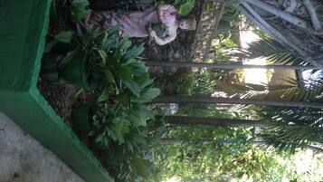 A statue of a woman in a garden with lush greenery and a stone wall.