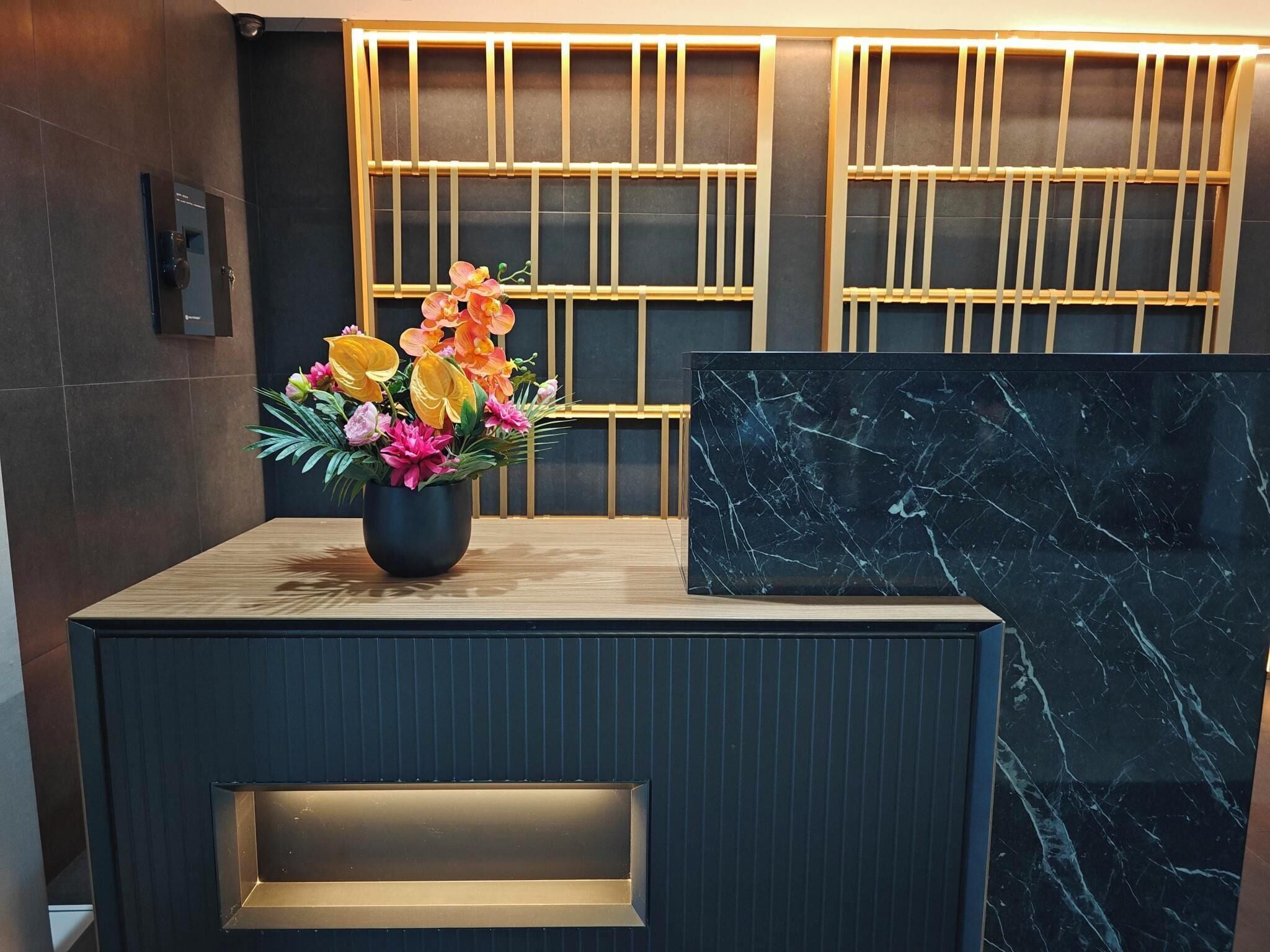 En receptionsdisk med en vas med blommor, en marmordekoration och en modern design.