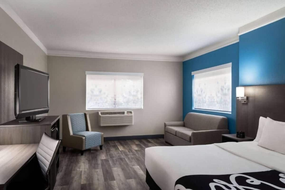 Une chambre d’hôtel comprenant un lit, deux fauteuils, un téléviseur et un appareil de climatisation.