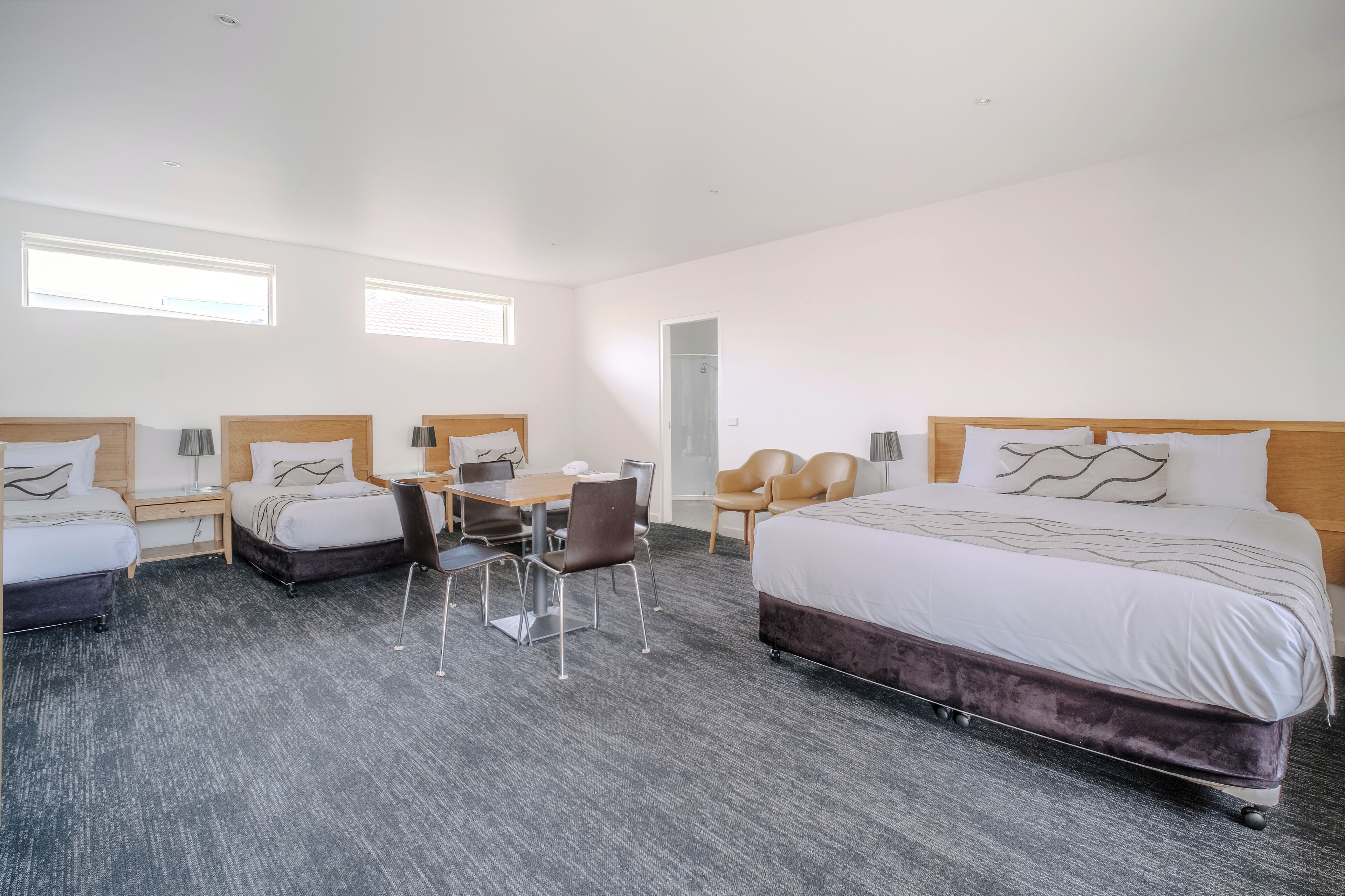 Une chambre d’hôtel avec un grand lit, deux petits lits, un bureau avec des chaises et un canapé.
