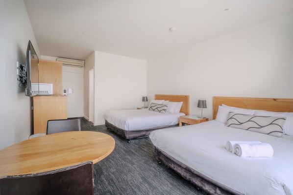 Una habitación de hotel con dos camas, un escritorio, un televisor y un minibar.