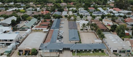 An aerial view of a residential area with houses, a parking lot, and a road.