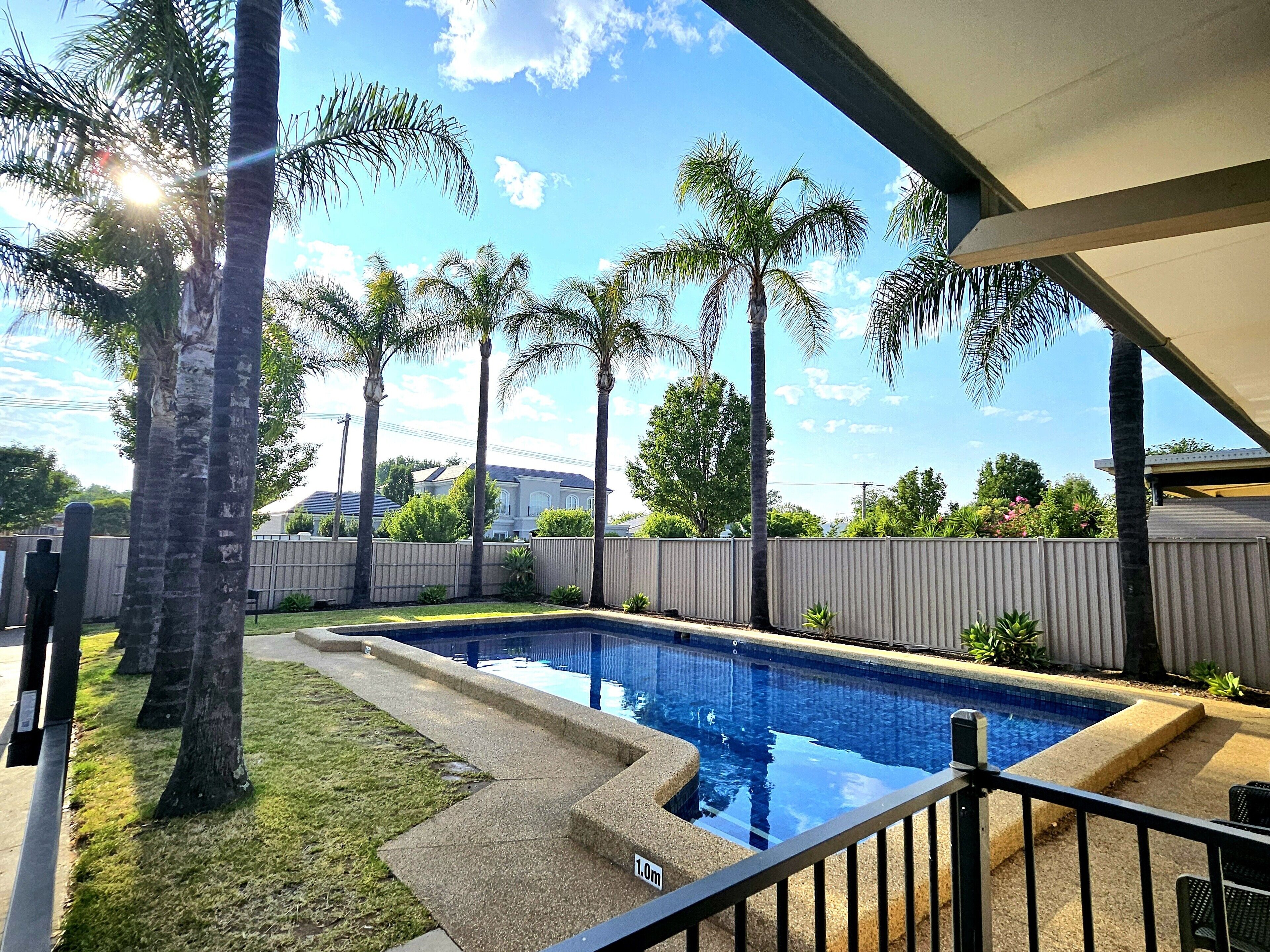 Una piscina al aire libre, sillones reclinables de piscina