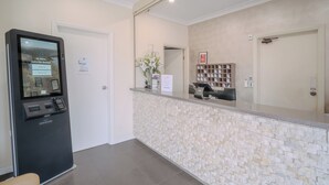 A reception area with a check-in kiosk, a counter with a mirror, a door, and a small plant. - Wyndhamere Motel Shepparton (Shepparton)