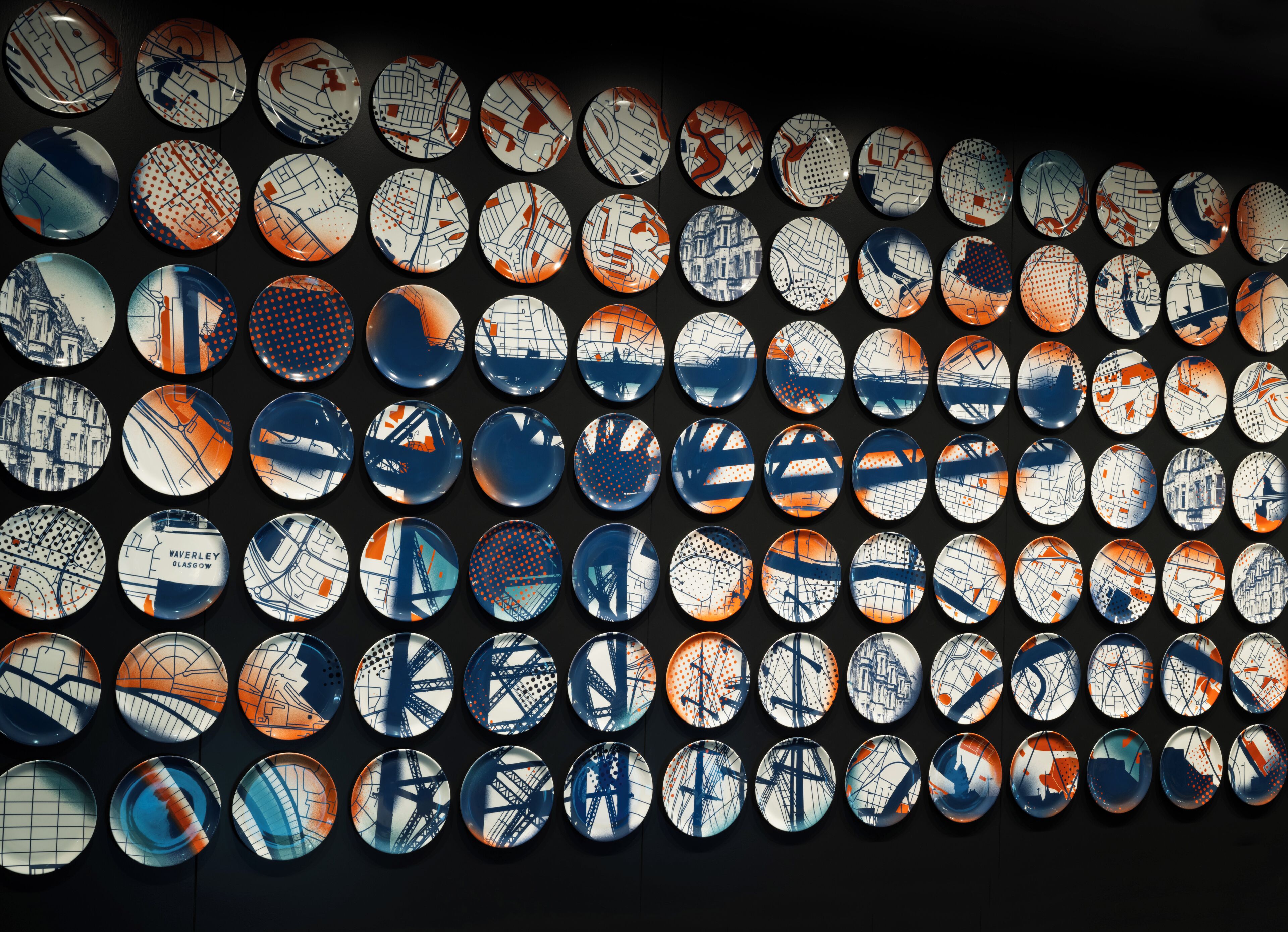 A wall of circular plates with various cityscape designs.