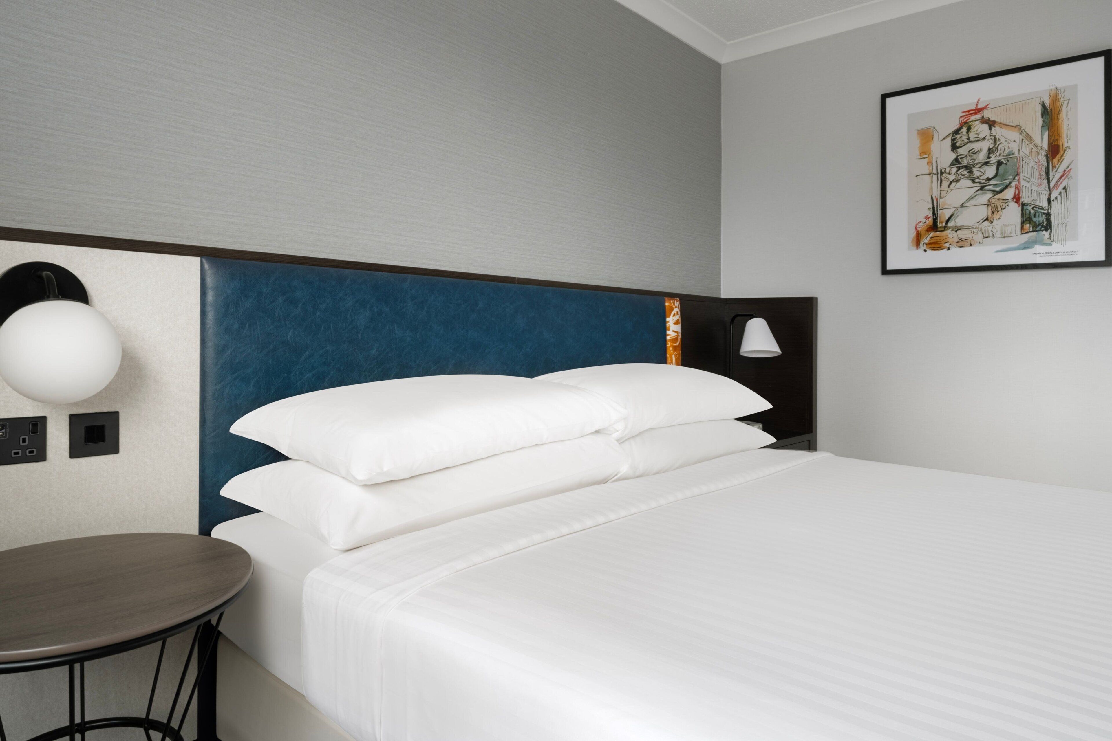 Ein Hotelzimmer mit einem Bett, einem runden Tisch und einer Wandlampe.