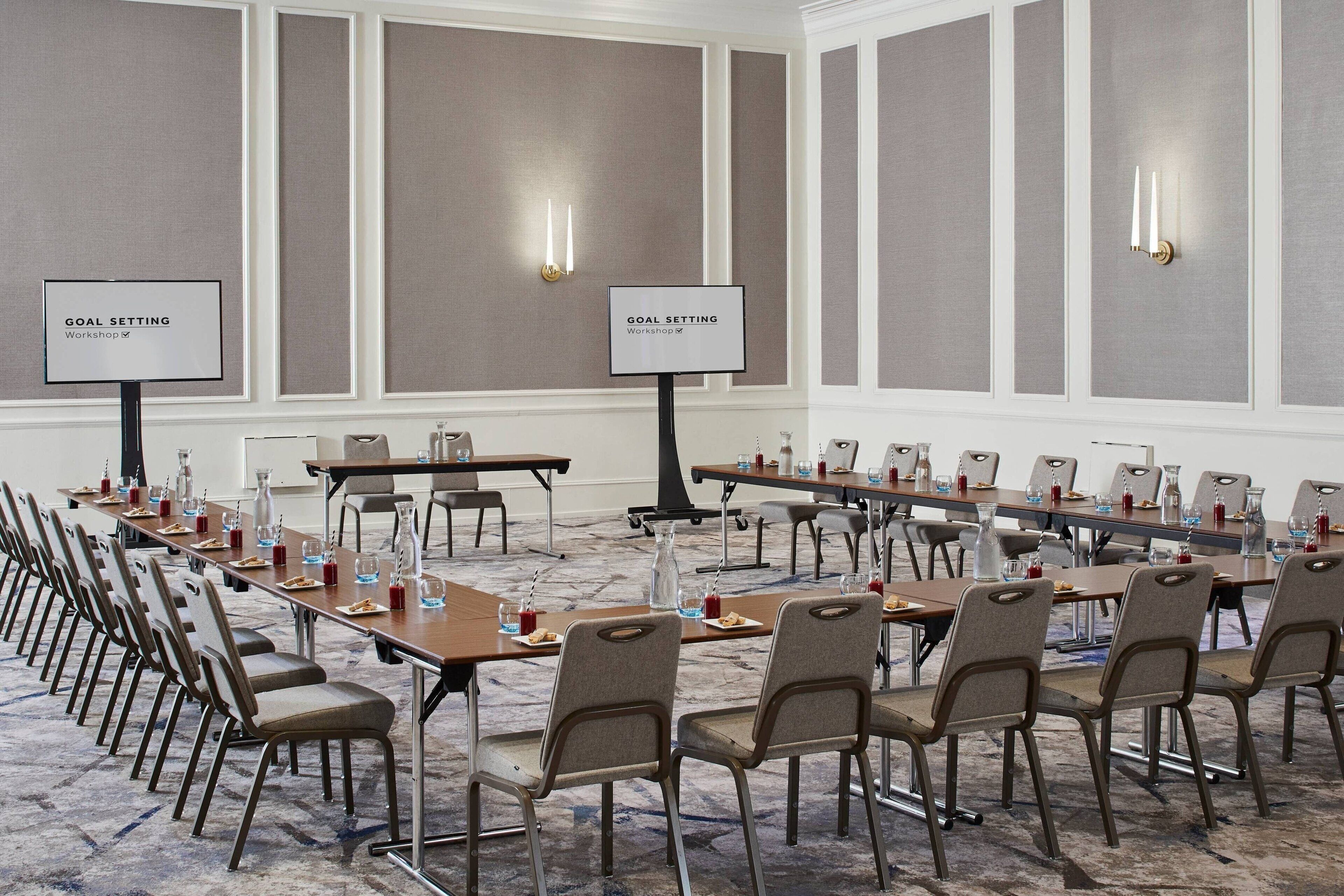 A conference room with long tables, chairs, and two goal setting signs on stands.