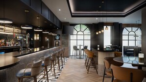 A modern bar area with a bar counter, seating, and a large window.