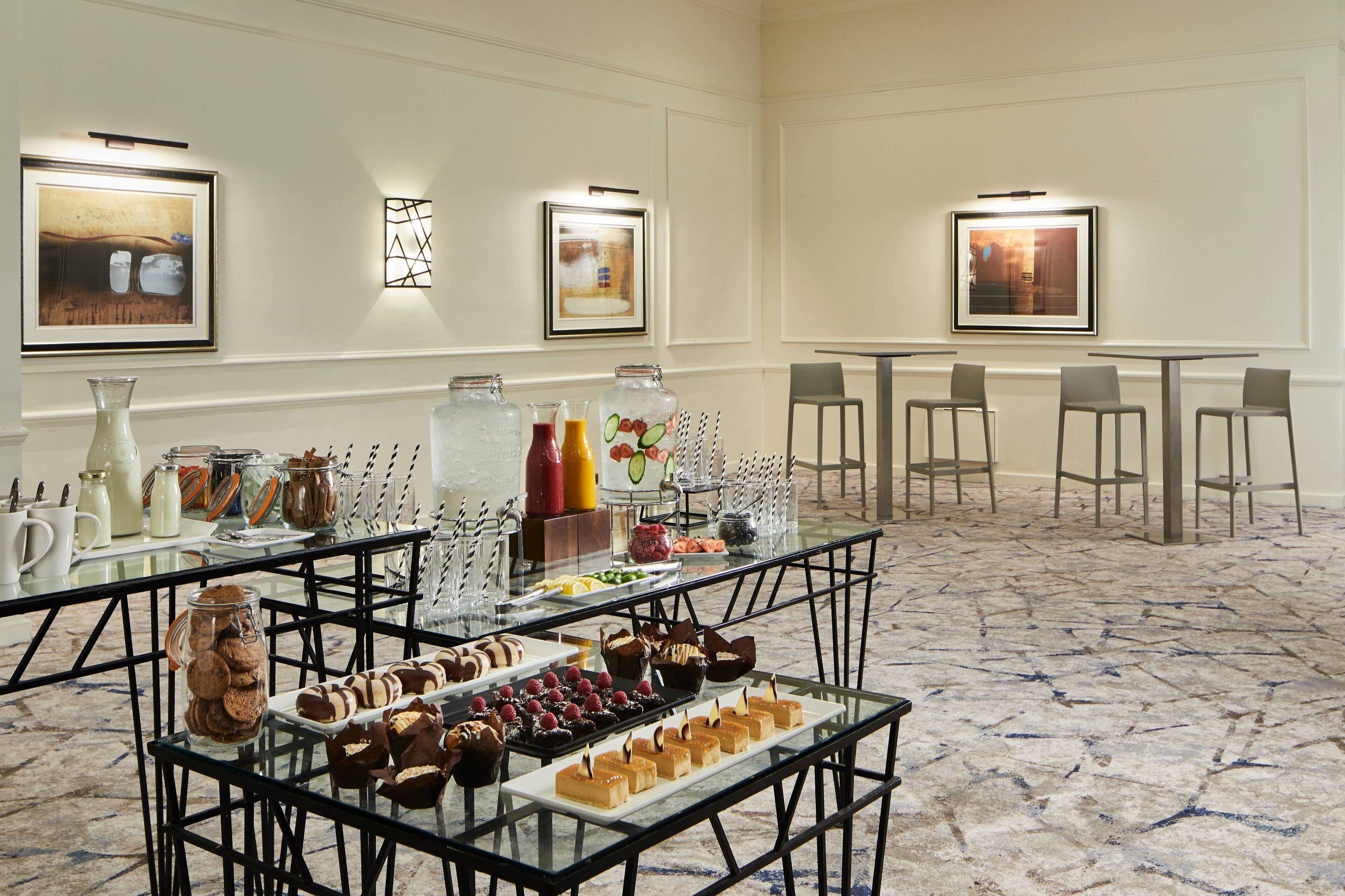 A buffet setup with various food items and beverages, arranged on tables with chairs.
