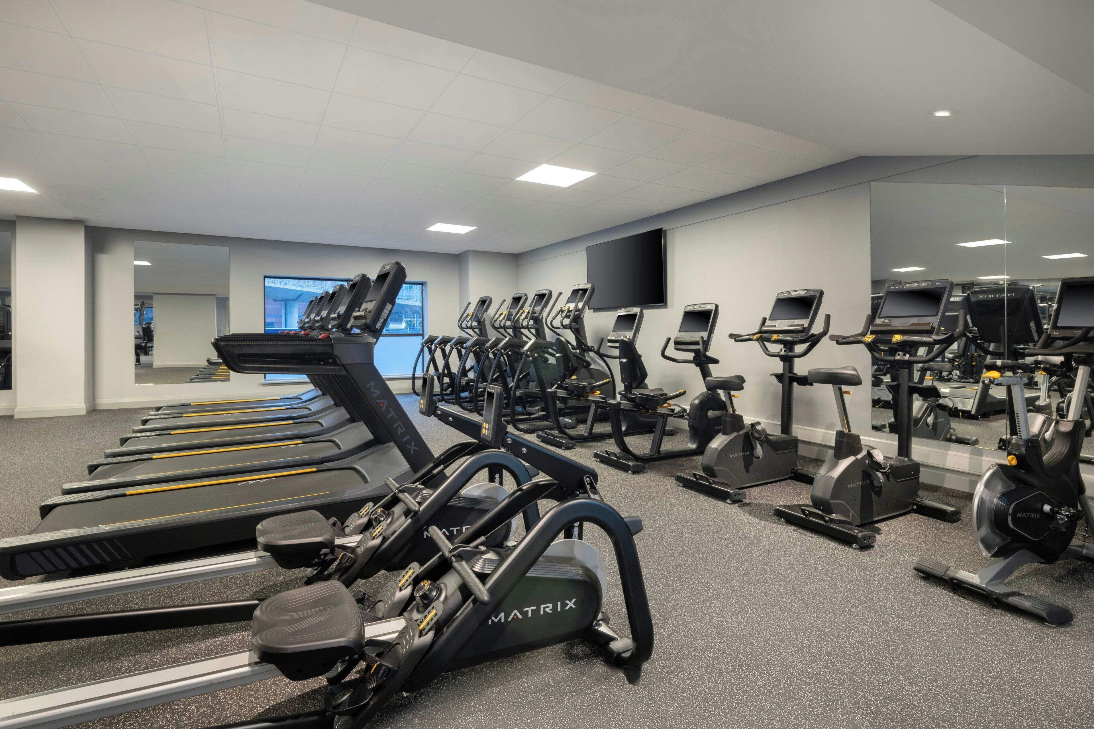 A gym with multiple treadmills, elliptical machines, and stationary bikes.
