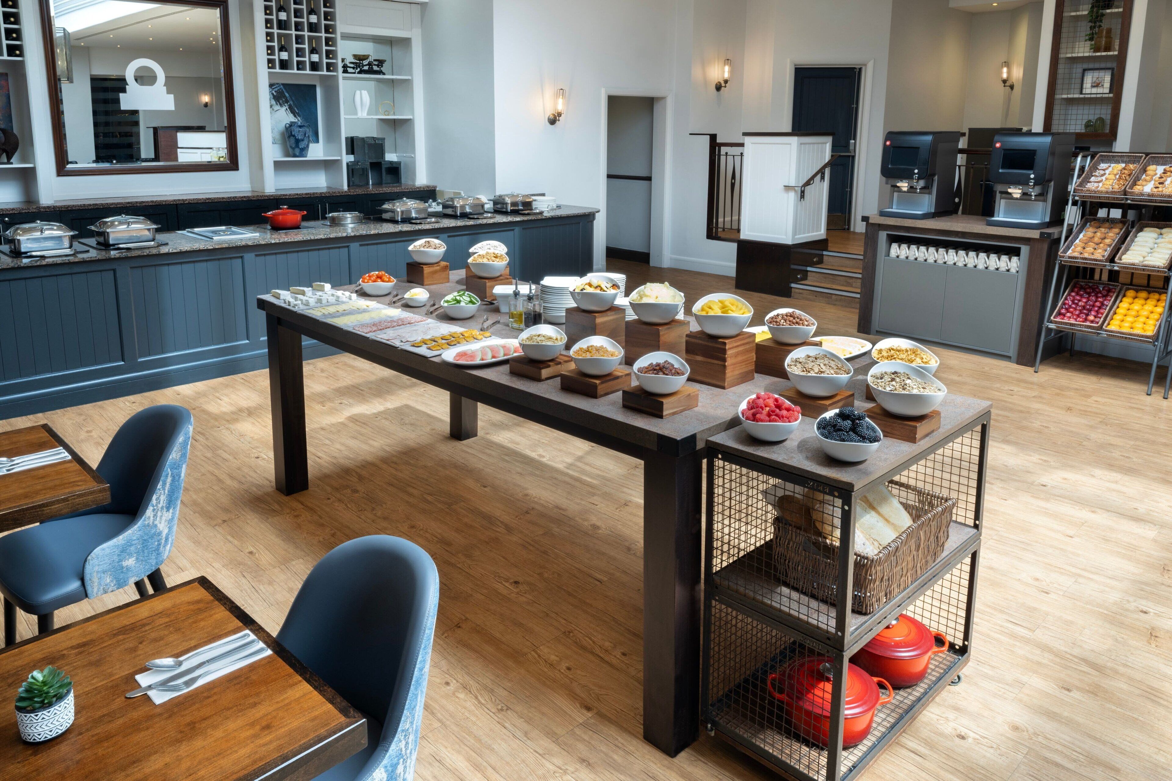 A buffet setup with various food items and a coffee station in a modern kitchen area.