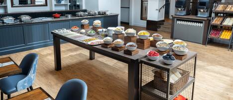 Montaje tipo bufé con diversos alimentos y una estación de café en una cocina moderna.