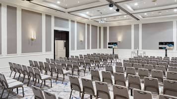 A conference room with rows of chairs, a projector, and a screen displaying "WELCOME".