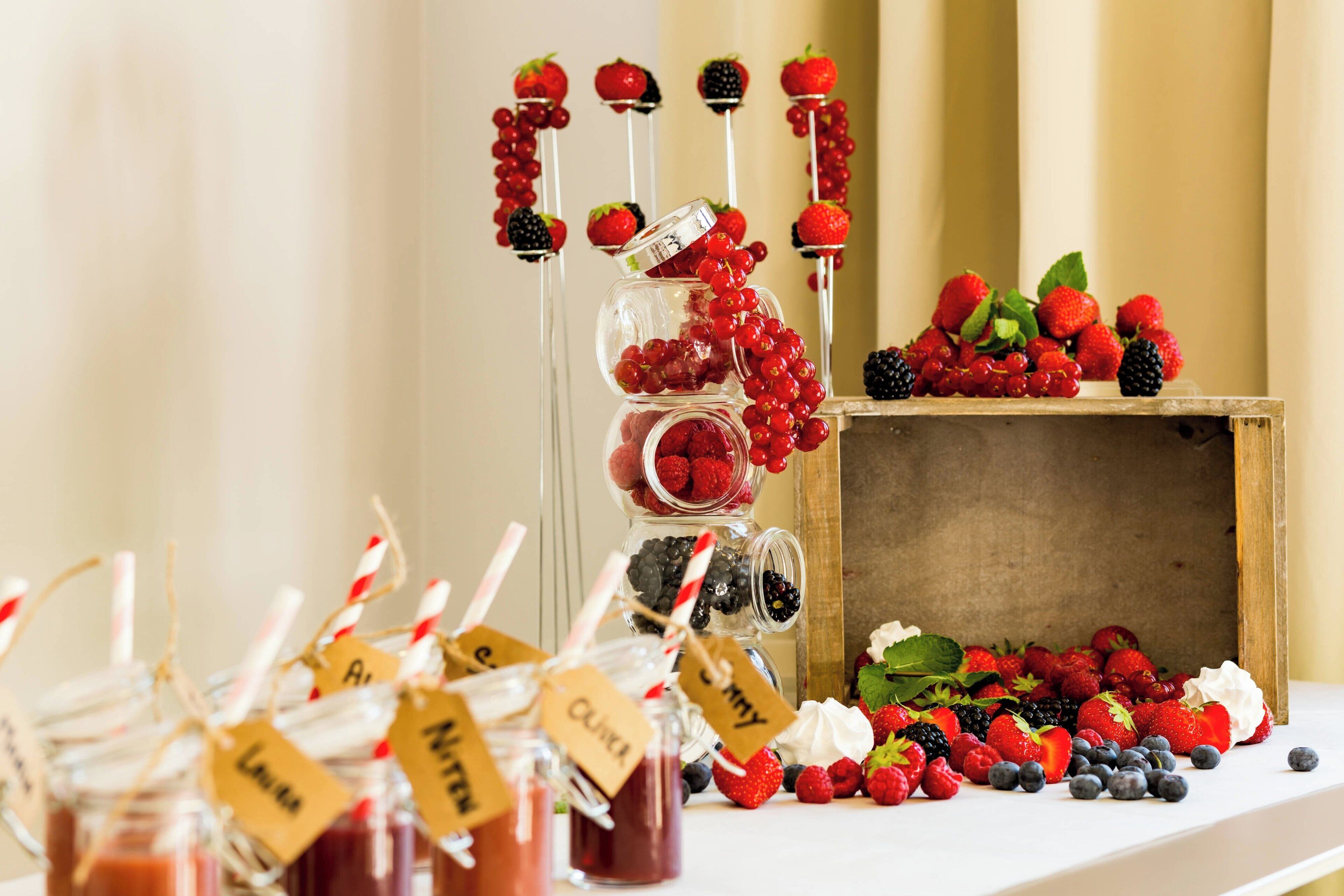 A table with various jars of jam and fresh berries, some with labels.