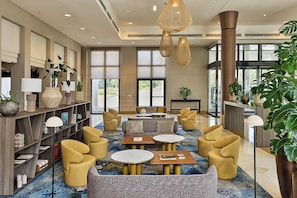 A modern lobby with seating areas, a reception desk, and large windows. - Paris Marriott Charles de Gaulle Airport Hotel (Roissy-en-France)