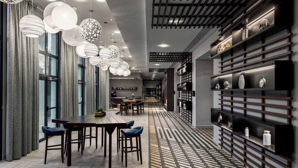 A modern interior with a long dining table, multiple hanging lights, and a patterned floor. - Paris Marriott Charles de Gaulle Airport Hotel (Roissy-en-France)