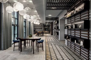 Un interior moderno con una larga mesa de comedor, varias lámparas colgantes y un suelo con diseño.
