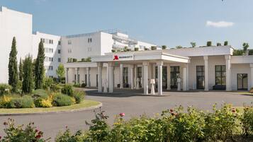 A modern Marriott hotel with a central courtyard, white columns, and a landscaped garden with roses.