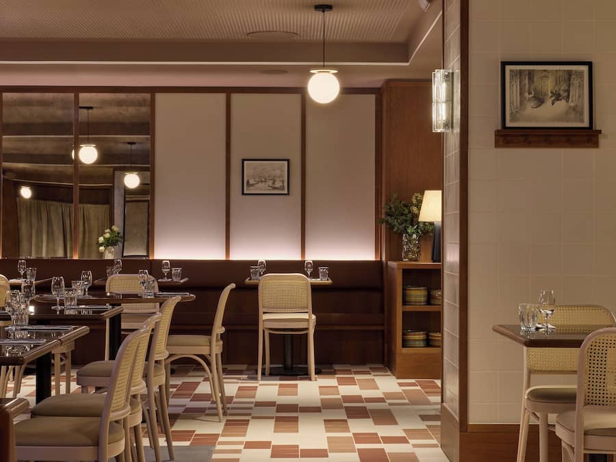Un restaurant avec un sol à carreaux, des meubles en bois et des luminaires suspendus.