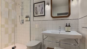 Ein modernes Badezimmer mit Duschkabine aus Glas, Waschbecken in Weiß mit Chromarmatur und einem gerahmten Bild an der Wand.
