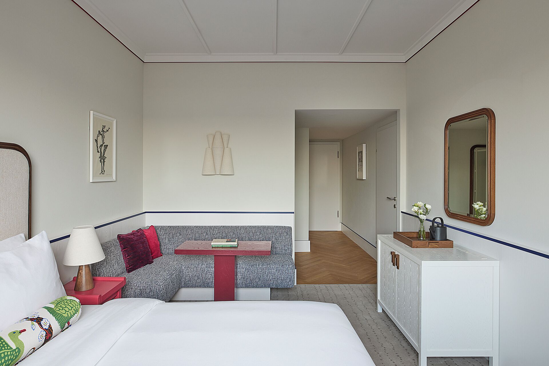A hotel room with a bed, a small table, a sofa, a dresser, and a mirror.