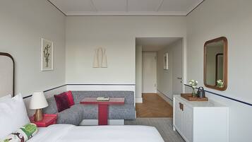 A hotel room with a bed, a small table, a sofa, a dresser, and a mirror.