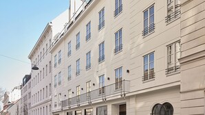 Un immeuble à plusieurs étages, doté d’une façade symétrique, de grandes fenêtres et d’un balcon orné d’une rambarde en métal.