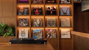 Un mur orné de pochettes d’albums encadrées et, au premier plan, une table de mixage de DJ.